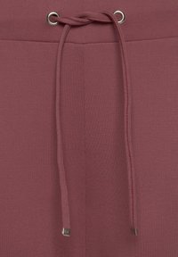 Bordeaux trekbroek met een gladde textuur, metalen oogjes en platte trekkoorden met metalen punten. Minimalistisch ontwerp.