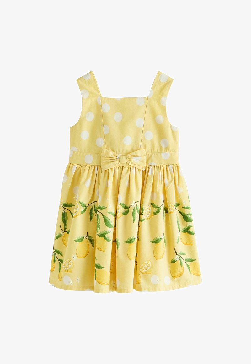 Robe jaune sans manches à pois blancs, imprimé citron et feuilles sur la jupe, avec un nœud à la taille.