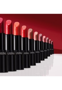 Läppstift i olika nyanser står på rad; livliga röda, mjuka nude-färger och rosa i cylindriska svarta rör med präglade logotyper och glänsande ytor.
