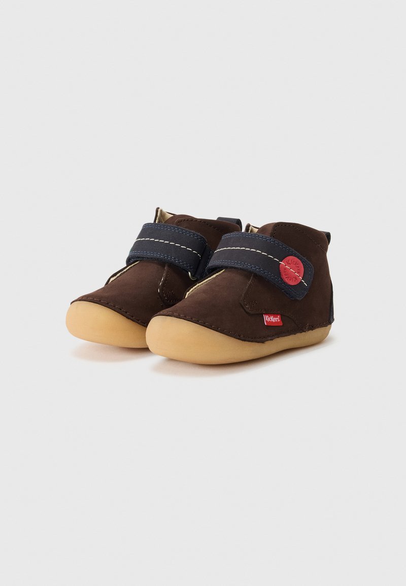 Scarpe per bambini di colore marrone con cinturini in velcro blu e suole beige, con loghi rossi del marchio sui cinturini e sui lati, su uno sfondo bianco.