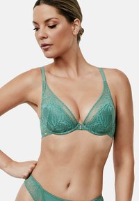 Soutien-gorge en dentelle bleu-vert avec un décolleté en V, présentant des motifs floraux, des bretelles ajustables et un petit fermoir métallique au centre.