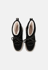 Bottines en suède noir avec un intérieur en fourrure blanche, des lacets à motifs noir et blanc, et une semelle en caoutchouc beige. Boucle de tirage à l'arrière.