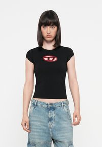 Black fitted t-shirt with short sleeves, featuring a red oval logo at the chest, paired with light blue denim shorts, visible buttons and pockets.