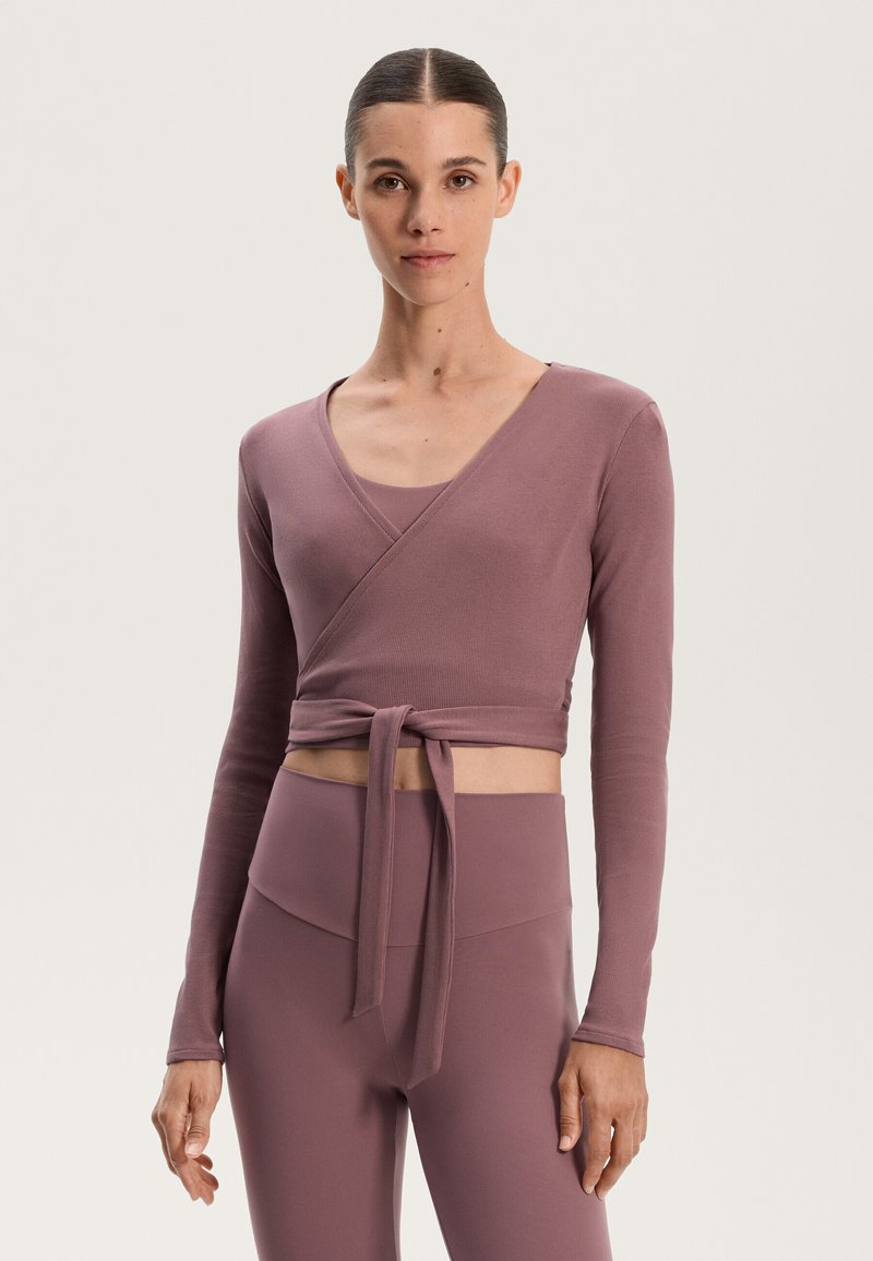 Ribbed, wrap-style top in dusty mauve, with long sleeves and a tie at the waist, paired with high-waisted, matching leggings.