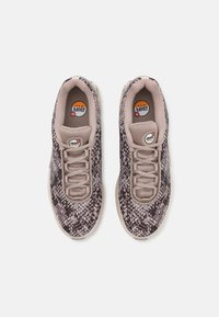 Sneakers with a snake print design in shades of beige and brown, featuring a textured fabric upper, front lacing, and cushioned soles.