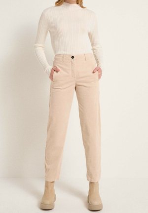 Pantalons en velours côtelé beige avec poches latérales, coupe droite et fermeture à un bouton, associés à un haut à manches longues à côtes légères.