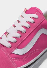 Baskets roses avec lacets blancs et bande latérale blanche, coutures détaillées et semelle en caoutchouc, vues en gros plan.