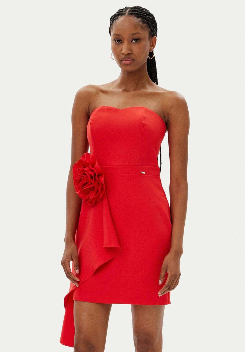 Vestito rosso senza spalline realizzato in tessuto aderente, con una grande accentuazione floreale e drappeggi laterali, dalla silhouette snella e una texture liscia.