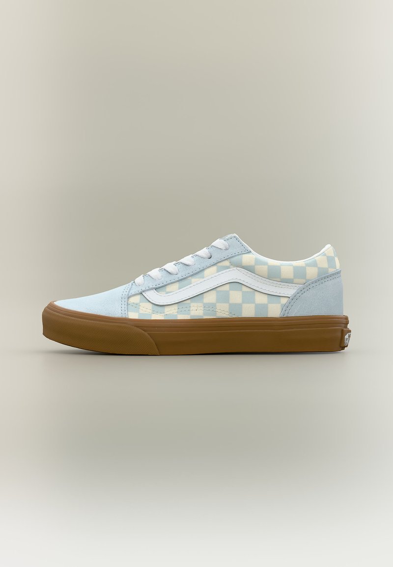 Baskets basses en daim bleu clair, motif à carreaux crème, bande blanche, lacets blancs et semelle en caoutchouc marron sur un fond neutre.
