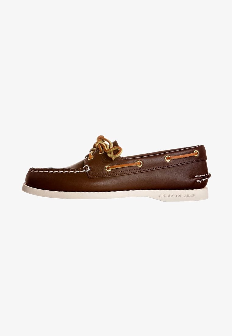 Chaussure bateau en cuir marron avec coutures blanches, lacets couleur fauve et semelle en caoutchouc blanche, vue de profil.