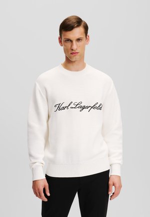 Kremo spalvos megztinis, su tekstūruotu mezgimo raštu ir įribuotomis rankovėmis bei apykakle. Priekyje juodas siuvinėtas "Karl Lagerfeld" logotipas.