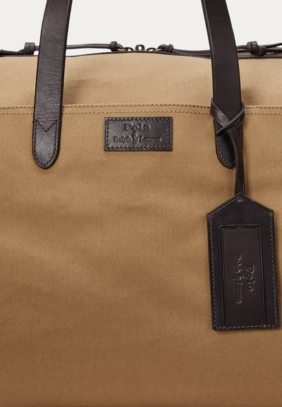 Tan canvas tote bag with dark brown leather handles, Polo Ralph Lauren logo patch, and matching leather tag attached to handle.