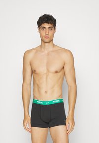 Boxer briefs neri con un elastico verde Nike, caratterizzati da una vestibilità aderente e da un tessuto liscio. Nessun elemento di design o motivo aggiuntivo.