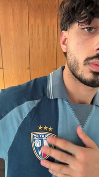 Μπλέ και ανοιχτό μπλέ ριγέ ρούχο ράγκμπι με σχεδίαση που περιλαμβάνει γιακά, με κεντημένο λογότυπο και τρία χρυσά αστέρια από πάνω. Υφή υφάσματος.