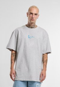 Gray oversized t-shirt made of cotton with a round neckline, featuring blue embroidered text on the chest and short sleeves.