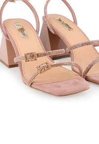 Tacones de ante en rosa empolvado con punta cuadrada, correas adornadas con acentos de cristal y un tacón geométrico grueso.