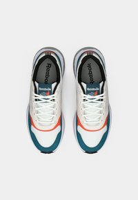 Para białych, turkusowych i pomarańczowych sneakersów Reebok z sznurówkami, widziana z góry na gładkim białym tle.