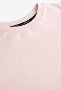 Svetloružové bavlnené tričko s okrúhlym výstrihom, s vyrazeným logom "ALLSAINTS" na prednej strane, jemnou štruktúrou a minimalistickým dizajnom.
