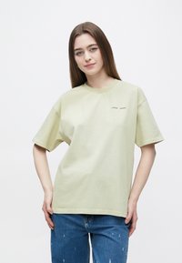 Hellgrünes Baumwoll-T-Shirt mit kurzen Ärmeln und Rundhalsausschnitt. Verfügt über dezente Markenlogos auf der Brust und eine lockere Passform.