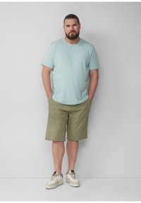 Jasnoniebieska bawełniana koszulka w połączeniu z oliwkowymi szortami. Casualowe sneakersy z białymi i kremowymi akcentami. Prosty design, luźny krój.