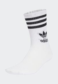 Fehér sportzokni bordázott textúrával, a tetején három vízszintes fekete csíkkal és az oldalon fekete Adidas logóval.