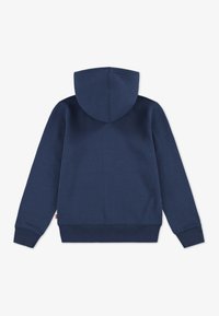 Mörkblå hoodie med en rymlig huva, ribbade muddar och nederkant, samt en mjuk textur. Har en liten logotag vid den nedre vänstra sömmen.