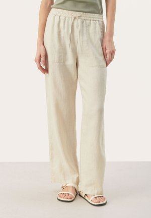 Linnedragt med vide ben i lysebeige med elastik i taljen og to forlommer. Kombineret med neutrale sandaler.