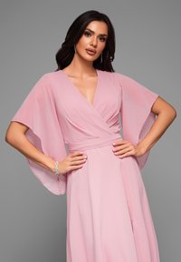 Rosa chiffongklänning med utställda ärmar, djup V-ringning och åtsittande midja. Slät textur, golvlång design och figurnära silhuett.