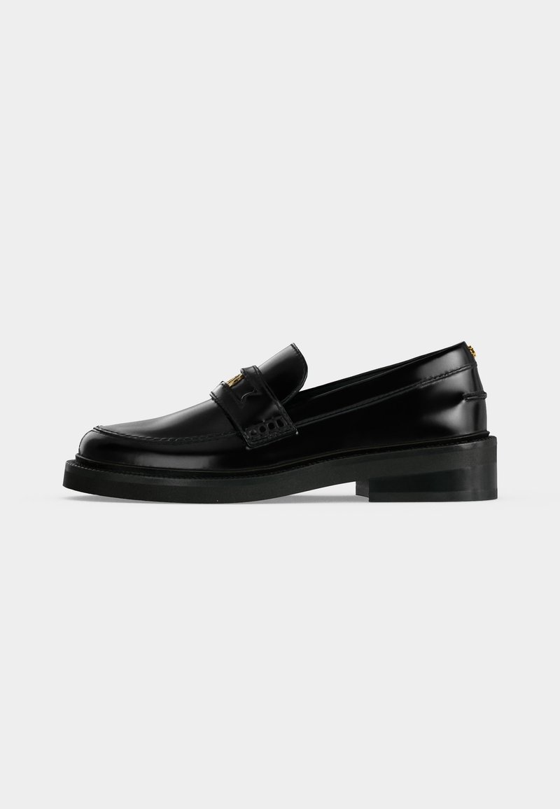 Mocassin en cuir noir poli avec un petit talon carré, surpiqûres moc toe et une bride décorative sur le dessus.
