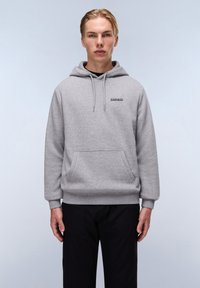 Grijze hoodie met een kangoeroezak, capuchon met koord en klein logo op de borst. Zachte textuur en een ontspannen pasvorm, gedragen boven zwarte broek.