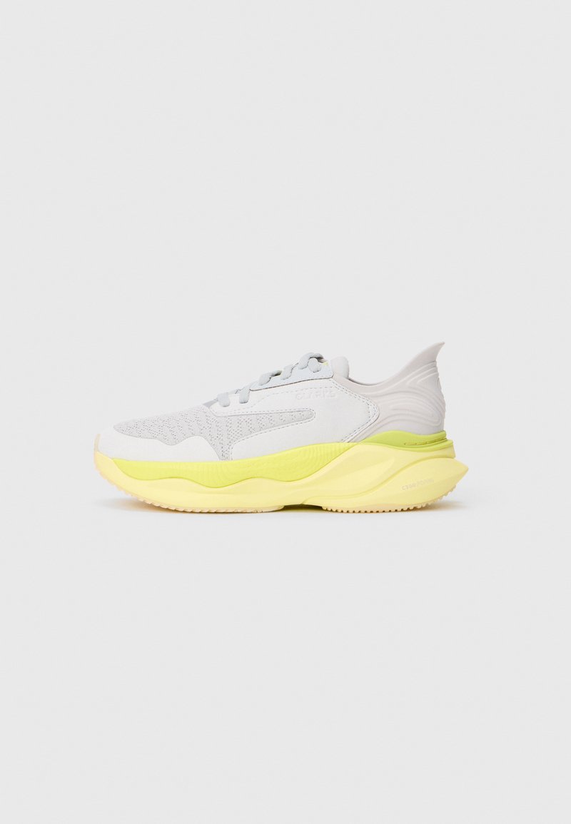 Sneaker atletico bianco e grigio chiaro con suola gialla imbottita e design a onda su uno sfondo grigio semplice, vista laterale della scarpa destra.
