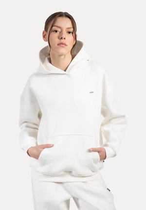 Witte hoodie van zacht materiaal, met een voorzak, geribde manchetten en een subtiel logo op de borst. Soepele textuur.