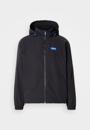Schwarze leichte Jacke mit Kapuze, Frontreißverschluss, zwei Taschen und blauem Logo. Verfügt über elastische Bündchen und Kordelzugsdetails an der Kapuze.