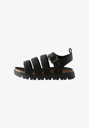Zwarte leren sandalen met vier brede banden, een gestructureerd oppervlak, een verstelbare gesp, een kurken voetbed en een robuuste zwarte rubberen zool.