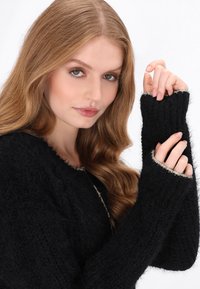 Schwarzer Strickpullover mit strukturiertem Finish, weiten Ärmeln und rundem Ausschnitt. Verfügt über kontrastierende graue Abschlüsse an den Bündchen.