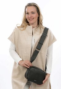 Borsa a tracolla in pelle grigia con forma arrotondata, superficie testurizzata e tracolla regolabile. Caratterizzata da una chiusura lampo e un branding discreto.