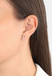 Pendientes de botón de plata de ley que presentan una gema rectangular transparente. Superficie suave y pulida con un diseño minimalista.