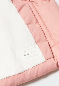 Růžová polstrovaná bunda s měkkým bílým fleecem, obsahující štítek na jméno a telefon, umístěný na vnitřní levé straně.