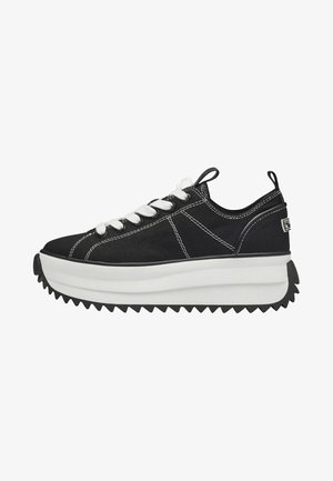 Black canvas sneaker with white laces, a thick white platform sole, and a zigzag black rubber outsole; features contrasting stitching details.