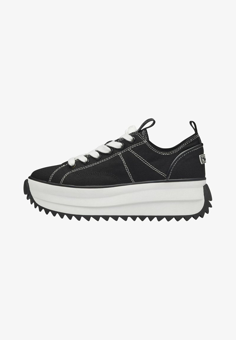 Zapatilla negra de lona con cordones blancos, suela gruesa blanca tipo plataforma y suela de goma negra con diseño zigzag; presenta detalles de costura en contraste.