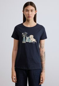 Μπλε βαμβακερό t-shirt με γραφικό που απεικονίζει ένα σκύλο και ανθοδέσμη δίπλα σε μπότες. Κοντά μανίκια και στρογγυλή λαιμόκοψη.