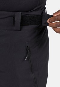Cintura nera regolabile con chiusura in velcro. Presenta una tasca laterale con zip per riporre oggetti su un tessuto liscio e resistente.