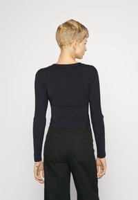 Must have pika-sleeve t-särk, sileda kanga ja ümar kaelusega. Omab keha ligi istuvat disaini ja ulatub vööni, pükste sisse pandud.