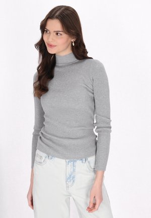 Maglione grigio a coste con collo alto, dalla forma aderente e maniche lunghe, abbinato a jeans a vita alta di un azzurro chiaro, caratterizzati da un design classico.