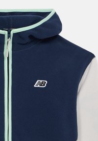 Navy blue and white fleece jacket with light blue trim, full front zipper, hood, and embroidered "NB" logo on chest.