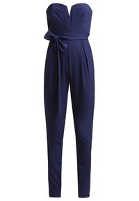 Combinaison bustier bleu marine avec encolure cœur, devant plissé, jambes fuselées et nœud de ceinture sur le côté gauche.