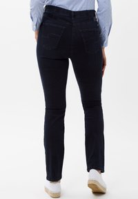 Donkerblauwe denimjeans met een slank design. Bevat twee achterzakken en heeft een gladde textuur. De pijpen zijn licht taps toelopend.