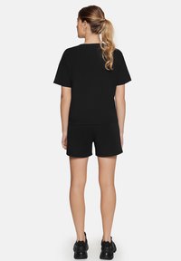 Sort bomulds T-shirt med korte ærmer, parret med matchende sorte shorts. Har en afslappet pasform og minimalistisk design.