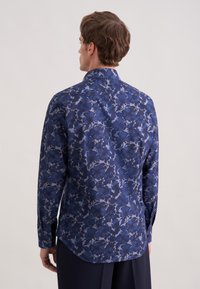 Koszula z długim rękawem w kwiatowy wzór w odcieniach niebieskiego, z klasycznym kołnierzem i zaokrąglonym dołem, wykonana z lekkiej tkaniny o gładkiej fakturze.