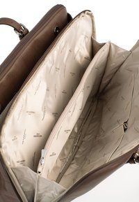 Het interieur van de bruine leren tas heeft meerdere vakken, een crèmekleurige voering met het "HEXAGONA" patroon, en een ritsvak voor veilige opberging.